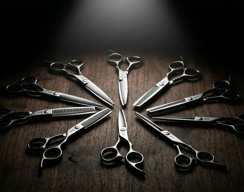 Multiple professional scissors arranged in circular mandala pattern on dark wood