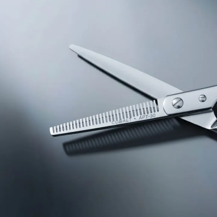 Juntetsu Aero Pro thinning scissors with blades open on a blue-grey background