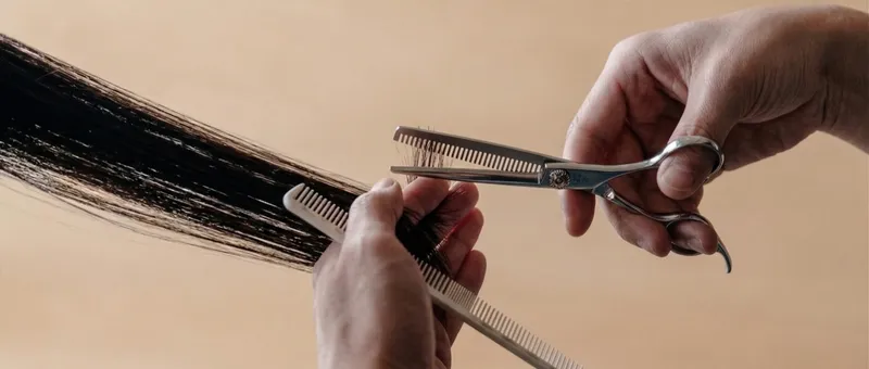Professional barber thinning shears held in hands with warm studio lighting
