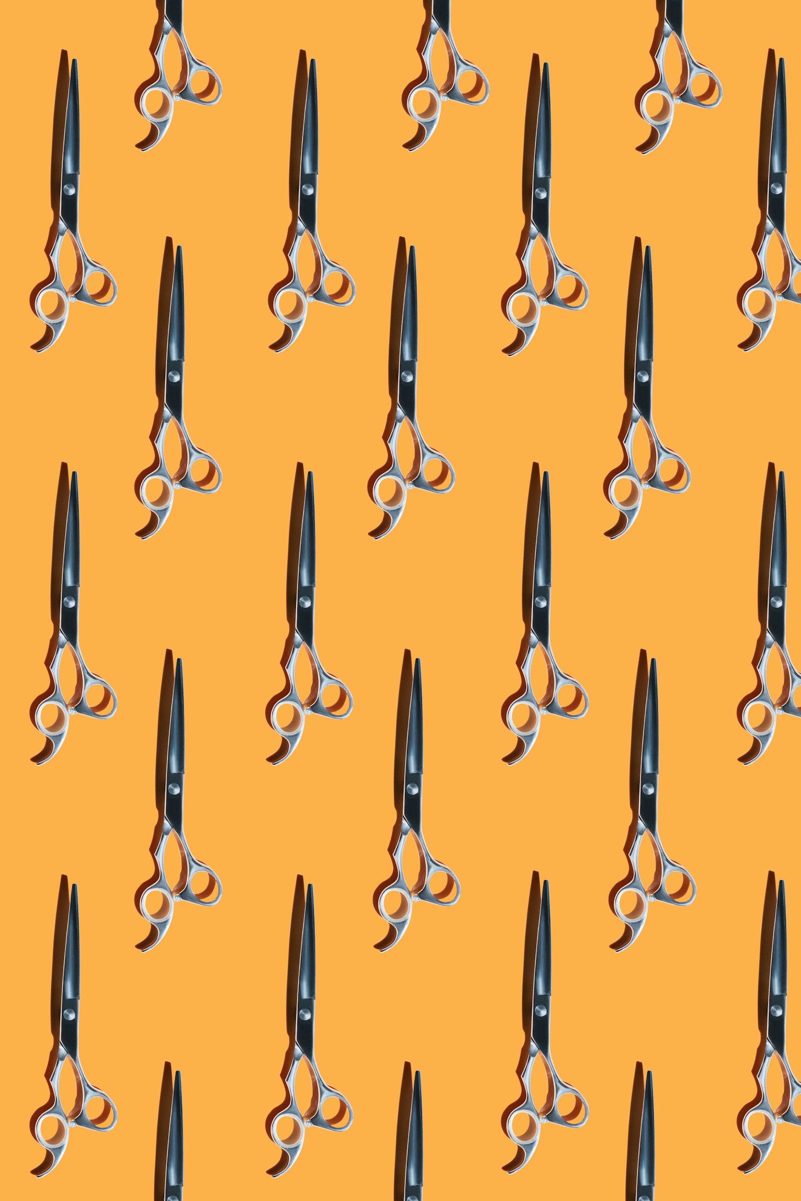 Multiple barber shears arranged on a yellow background